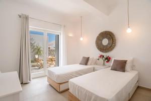 Habitación blanca con 2 camas y balcón. en Deluxe Maisonette With Private Jacuzzi, en Molos Parou