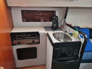 a small kitchen with a sink and a microwave at Dormir num veleiro em Lisboa in Lisbon
