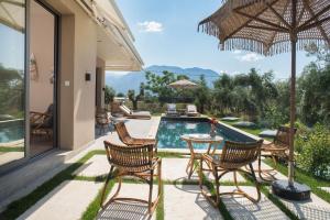 a patio with chairs and an umbrella and a pool at Elaia Grove in Kalamata