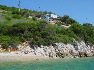 a house on top of a hill next to the water at Villa with breathtaking views and private beach in Agios Dimitrios