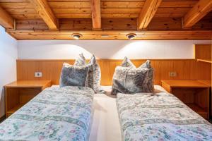 two beds in a room with wooden ceilings at Sirena Carezza Apartment Masarè in Carezza al Lago