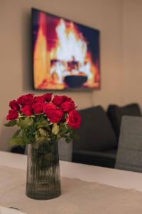 a vase filled with red roses sitting on a table at Lapinmaa Apartments in Rovaniemi