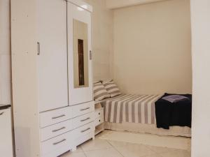a white bedroom with a bed and a mirror at Flats Beija-Flor in Itacaré