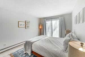 a white bedroom with a bed and a window at Mill Run 3D in Quechee