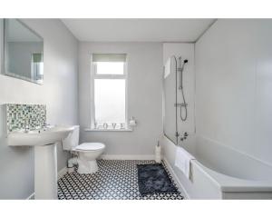a white bathroom with a sink and a tub and a toilet at Central Belfast Apartments Ravenhill in Belfast