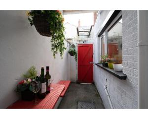 a red door and a red bench with wine bottles at Central Belfast Apartments Ravenhill in Belfast