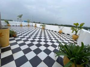 a balcony with a black and white checkered floor and potted plants at Le Poshe Luxury in Puducherry