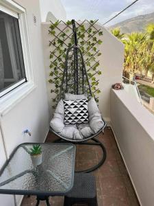 a swing on a balcony with a table and a window at Beach apartment Edem first floor in Perivolos