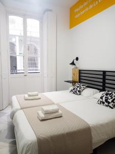 two beds in a white room with towels on them at Planeta Cadiz Hostel in Cádiz