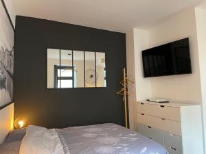 a bedroom with a black wall with a bed and a tv at Très Grand Studio - Terrasse in Strasbourg