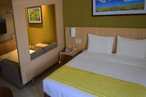a hotel room with a large bed and a desk at Suíte caldas novas (Risorte) in Caldas Novas