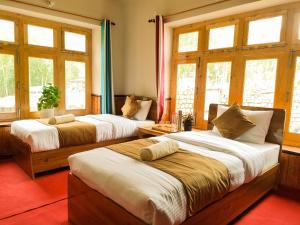 two beds in a room with windows at Sakti Homestay in Chimre