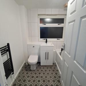 een witte badkamer met een toilet en een televisie bij Freshen-Up Stays in Oakengates