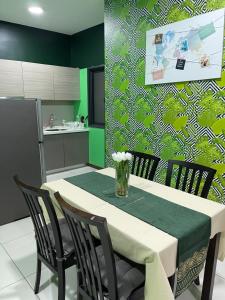 eine Küche mit einem Tisch mit Stühlen und einer grünen Wand in der Unterkunft Emira Shah Alam 2 BED ROOM in Shah Alam