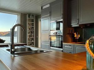 uma cozinha com um lavatório e um balcão com uma janela em Holiday home Huglo II em Nordhuglo
