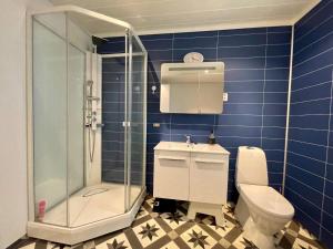 a blue tiled bathroom with a toilet and a shower at Holiday home Huglo II in Nordhuglo