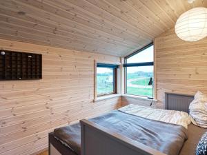 a bedroom with wooden walls and a bed with a window at Holiday home Stubbekøbing VII in Stubbekøbing