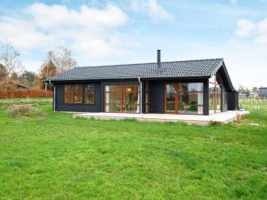 una casa negra en un campo con un patio verde en Holiday home Stubbekøbing VII, en Stubbekøbing
