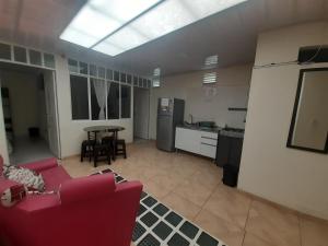 a living room with a red couch and a kitchen at San Francisco en Kennedy in Bogotá