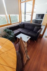 sala de estar con sofá negro y mesa en Hospes - Departamento en San Rafael