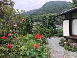 un jardin avec des fleurs rouges et des montagnes en arrière-plan dans l'établissement Fukurou no Oyado - Vacation STAY 71246v, à Fuefuki