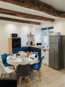 a kitchen with a table and chairs and a refrigerator at A La Mémoire de Merlin & SPA in Saint-Malon-sur-Mel