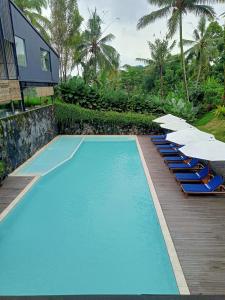 a pool with chairs and umbrellas next to a house at Teras Hotel Ijen Banyuwangi in Banyuwangi