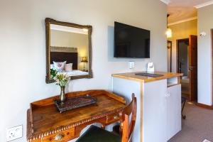 a room with a table with a mirror and a bed at Le Mahi Guest House in Langebaan