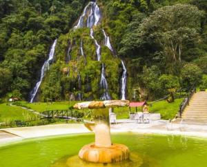 a fountain in front of a waterfall in a park at Araucarias Inn in Santa Rosa de Cabal