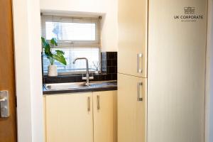 a kitchen with white cabinets and a sink and a window at 2 bed Apartment by UK Corporate Relocations Ltd in Warrington