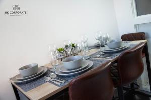 einen Esstisch mit Tellern, Tassen und Gläsern in der Unterkunft 2 bed Apartment by UK Corporate Relocations Ltd in Warrington