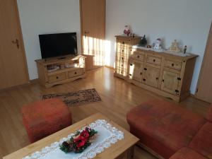 ein Wohnzimmer mit einem TV, einem Tisch und Stühlen in der Unterkunft Ferienhaus Gampe in Klingenthal