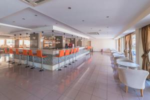 un restaurante con sillas naranjas y un bar en Filerimos Village Hotel, en Ialisos