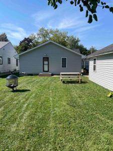 un patio con una casa y un banco en el césped en The Dollar House, en Albert Lea