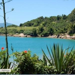 a view of a blue lake with trees and flowers at Casa Pé na Areia com Deck de Frente para o Mar, Pinheira, Praia de Cima, SC in Palhoça