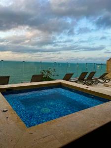 una piscina con sillas y el océano en el fondo en Hermoso apartamento con vista al mar y salida directa a la playa, en Cartagena de Indias