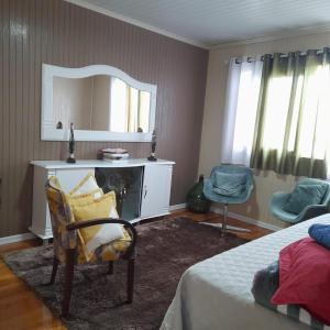 um quarto com uma cama, uma cadeira e um espelho em Casa Vista do Vale próxima ao Vale dos Vinhedos em Bento Gonçalves