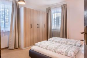 a bedroom with a bed and a cabinet and windows at Sirena Carezza Apartment Regenbogen in Carezza al Lago