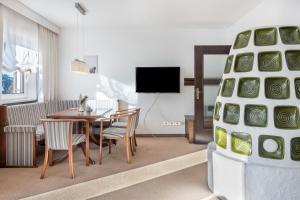 a living room with a table and chairs and a tv at Sirena Carezza Apartment Regenbogen in Carezza al Lago