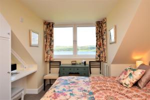 a bedroom with a bed and a desk and a window at The Neuk in Tighnabruaich