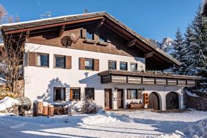 una casa en invierno con nieve en el suelo en Sirena Carezza Apartment Regenbogen, en Carezza al Lago