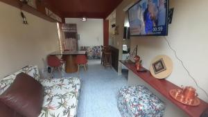 a living room with a couch and a tv on the wall at Aptos 1 quarto Ar Saraiva in Uberlândia