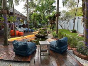 une terrasse en bois avec deux chaises et un étang dans l'établissement Pool Villas by Honey-5 miles from central Pattaya Beach, à Nong Prue