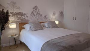 een slaapkamer met een groot wit bed met 2 lampen bij L'Orée du bois in Selongey