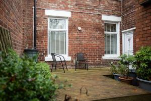 eine Terrasse mit zwei Stühlen vor einem Backsteingebäude in der Unterkunft Pine Street Home by #ShortStaysAway in Willington Quay