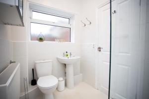 a white bathroom with a toilet and a sink at Pine Street Home by #ShortStaysAway in Willington Quay