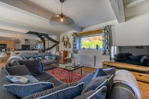 a living room with a couch and a tv at Ty-Voli - Magnifique Longère rénovée in Plougoumelen