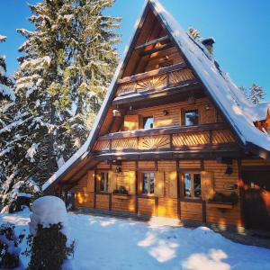 a log cabin in the snow with a tree at Holiday Home Tirol in Vlasic