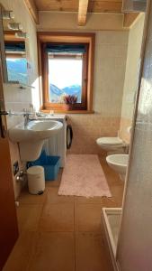 uma casa de banho com um lavatório, um WC e uma janela. em Sarochin Appartamenti em Livigno