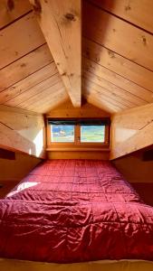 uma grande cama vermelha num quarto de madeira com uma janela em Sarochin Appartamenti em Livigno